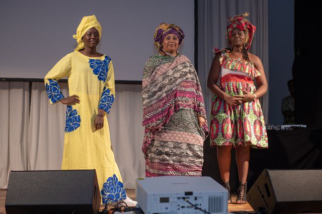Drei Models in traditioneller westafrikanischer Kleidung auf der Bühne