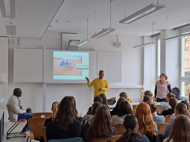 Referent vor einer Schulklasse, an der Wand die Projektion einer Präsentation über Mauretanien