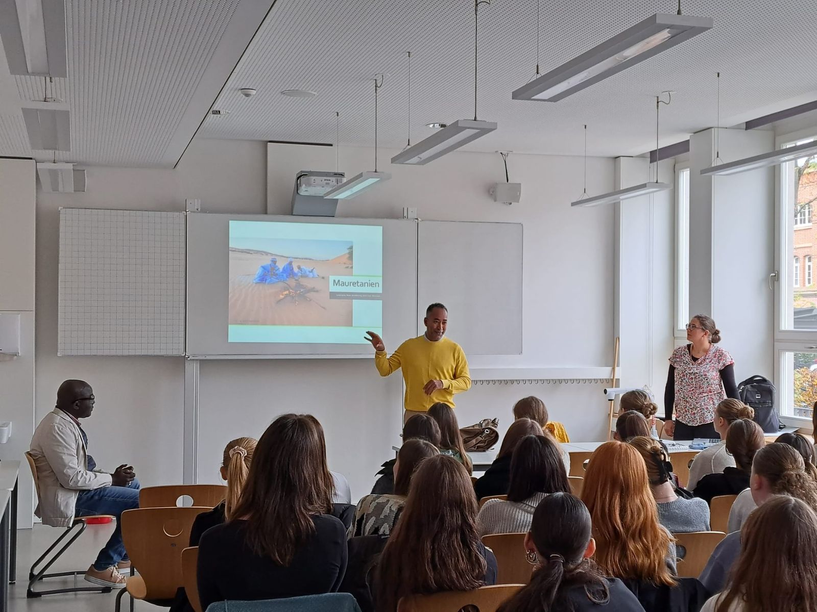 Referent vor einer Schulklasse, an der Wand die Projektion einer Präsentation über Mauretanien